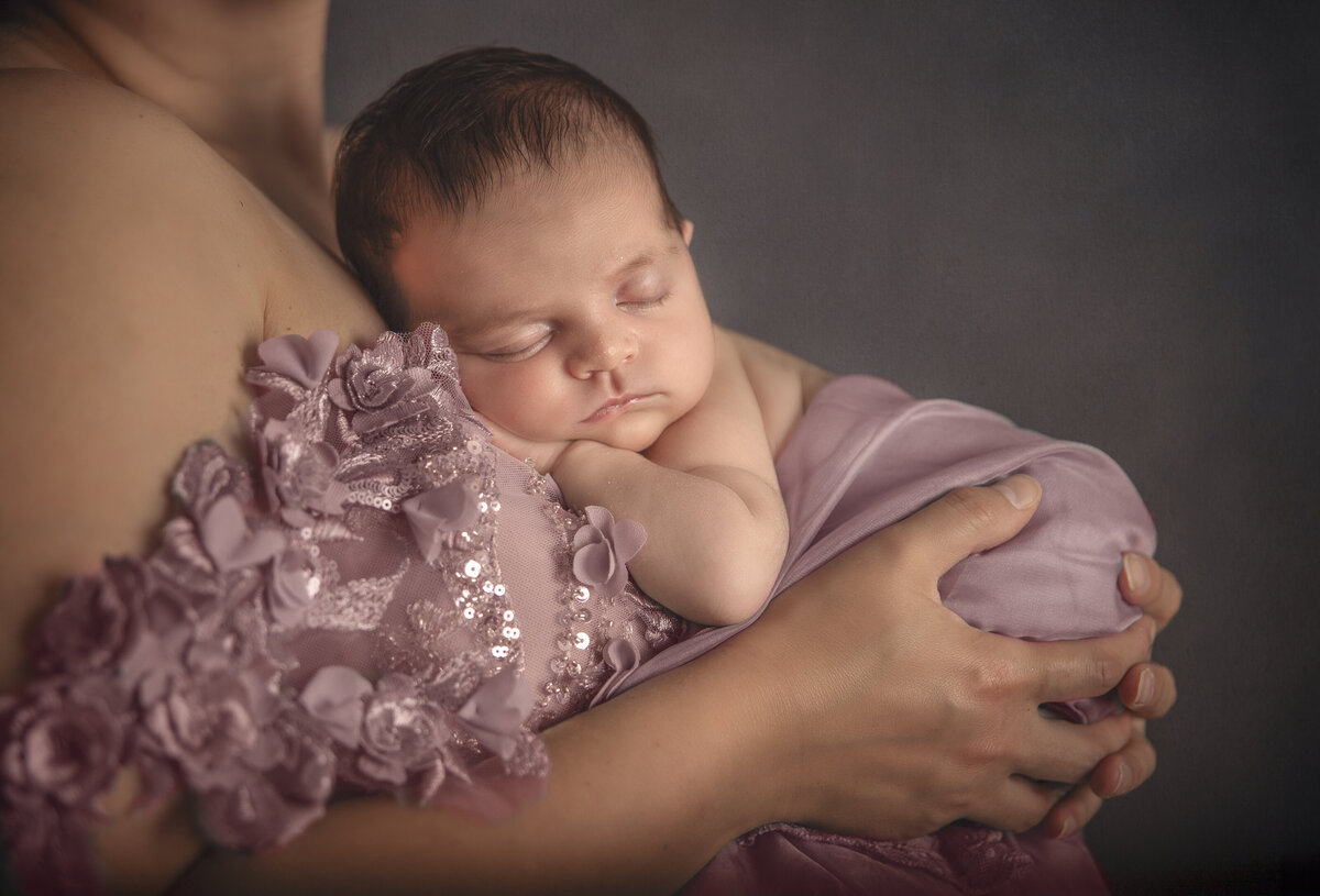 Best newborn photographer in ottawa Ontario takes close up photo of newborn girl  in mothers arms , all dressed in pink