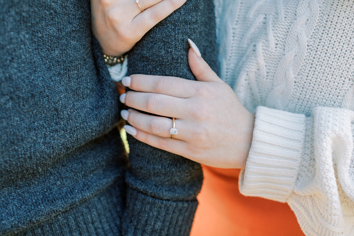 A yellow gold engagement ring is worn.