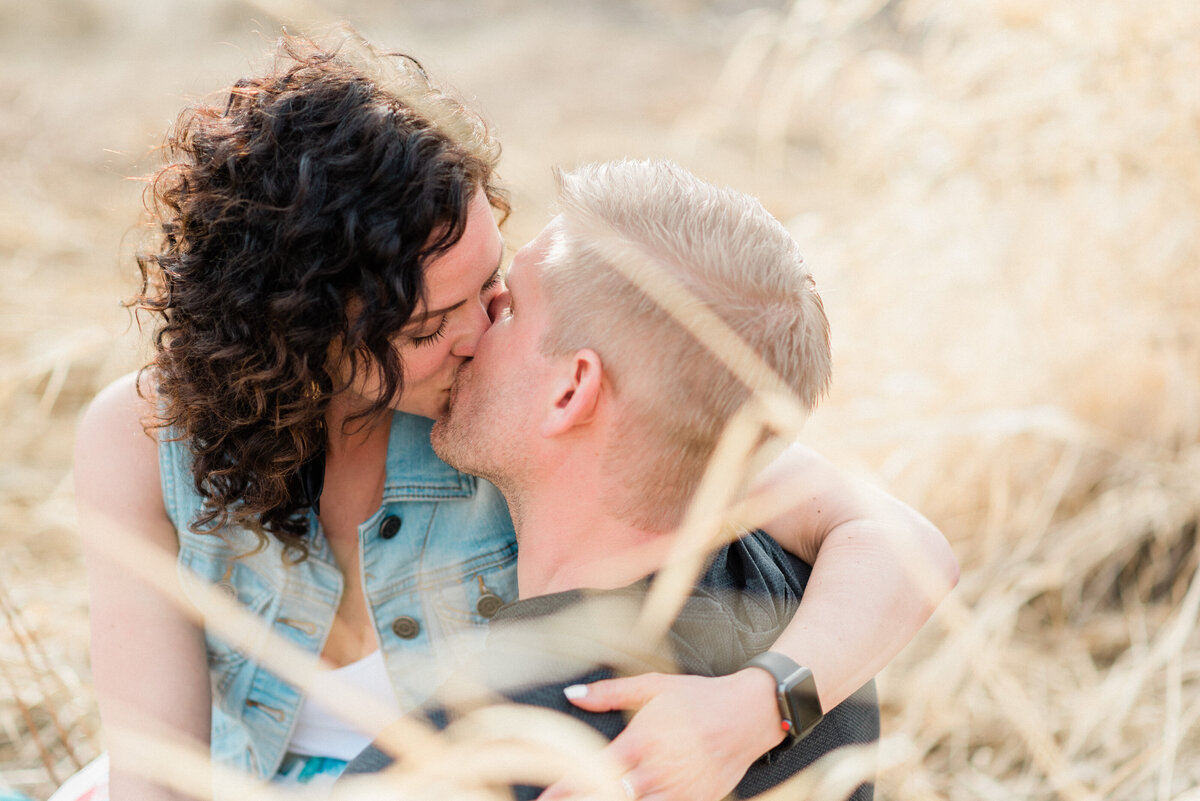 Couple kisses in whitewashed grasses.
