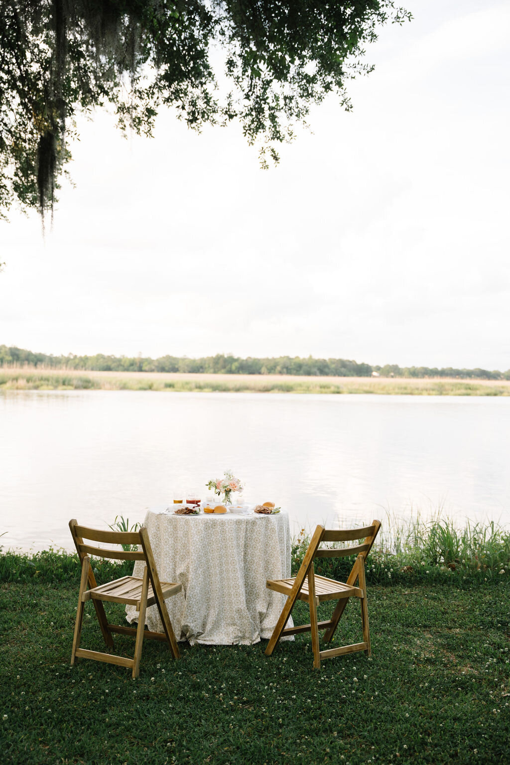 Wedding reception table with flowers in the grass overlooking the marsh water