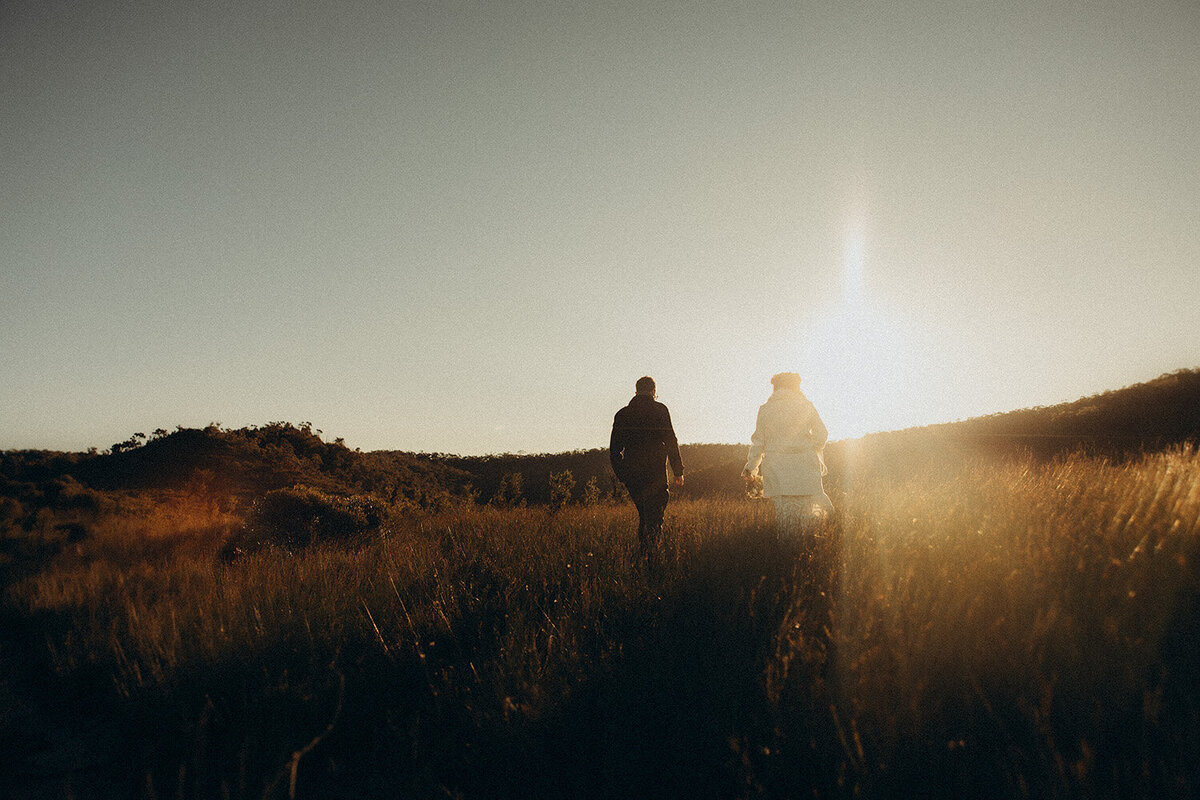Couple wandering through field during an elopement . Cinematic style photography , Sunshine Coast