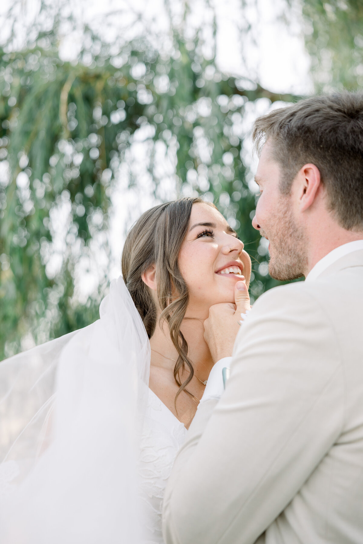bride smiling at groom while he gently holds her face