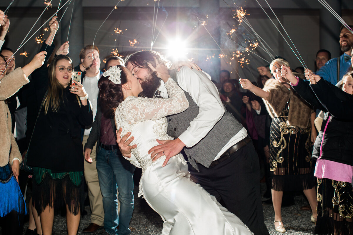 Wedding photo in Boone, NC of a groom dipping and kissing his wife during their sparkler exit at the end of their wedding day