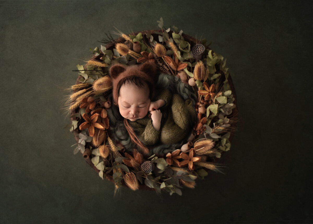 little boy all cureled up in  a wreath