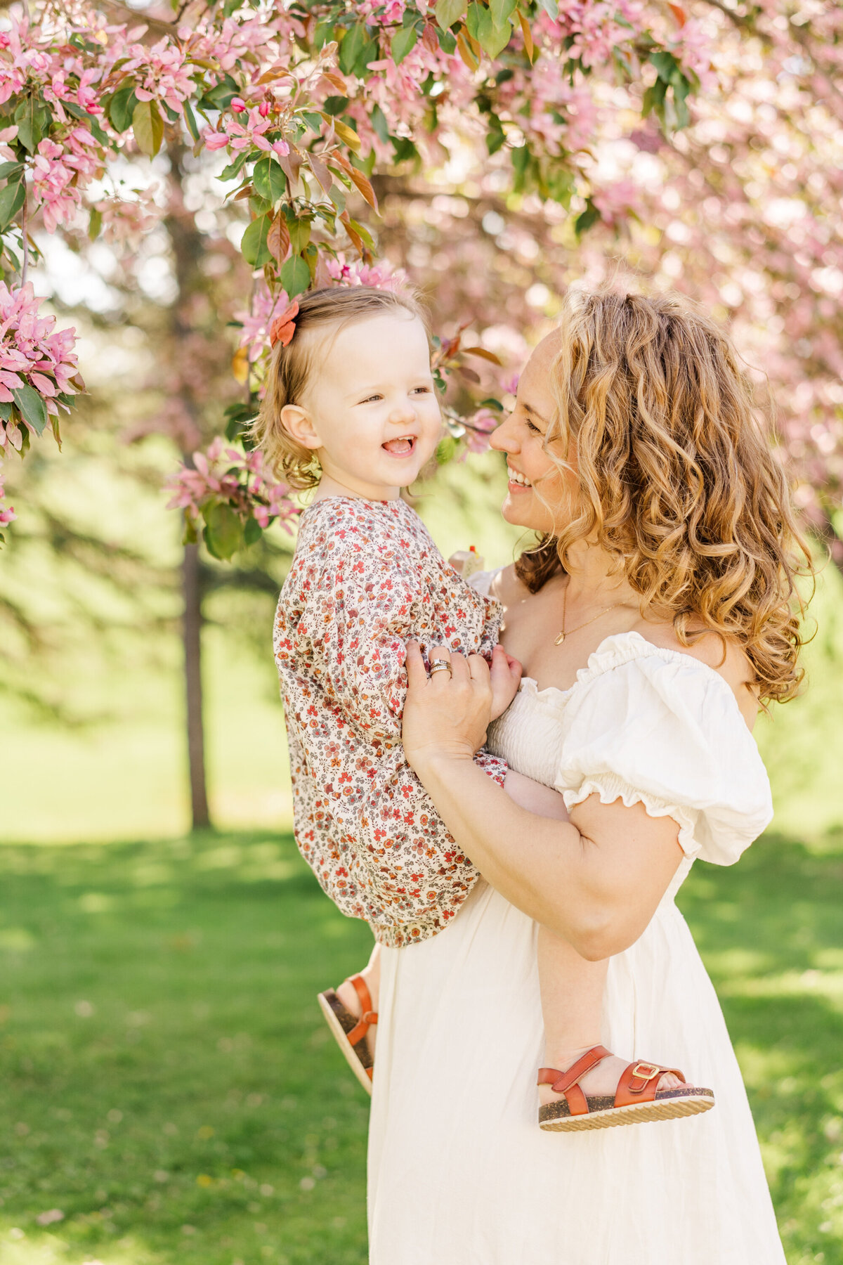 a mother tickles her daughter during an outdoor portrait session in Minneapolis