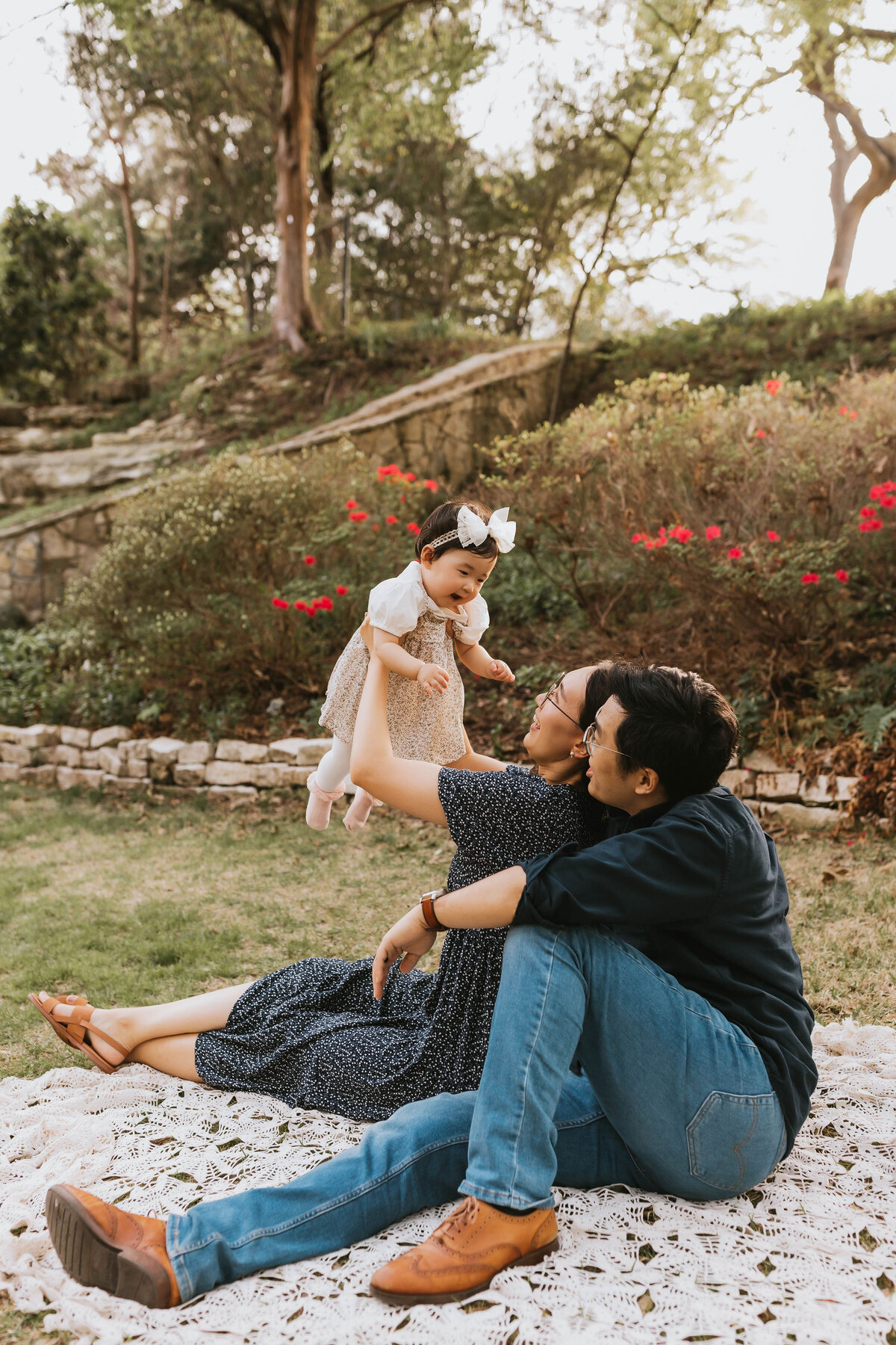 cute asian family sitting on a blanket playing with their baby girl