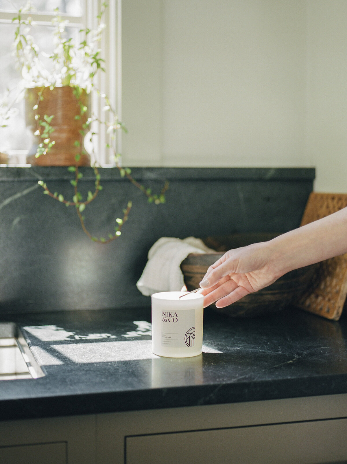 hand reaches to light a candle in afternoon sunlight, kitchen interior photography, film branding photoshoot