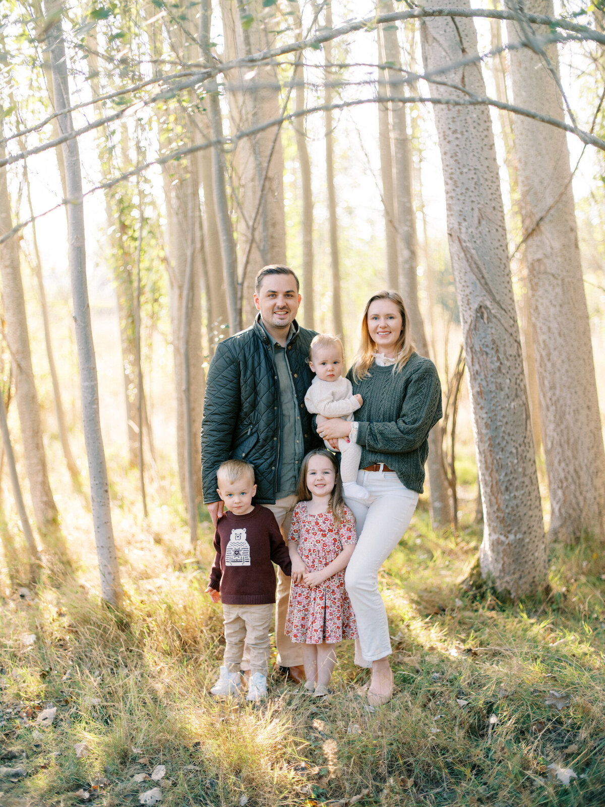 Seattle Family photos mini session in the fall with aspen trees and golden light. Family of four in fall wardrobe smiling at camera