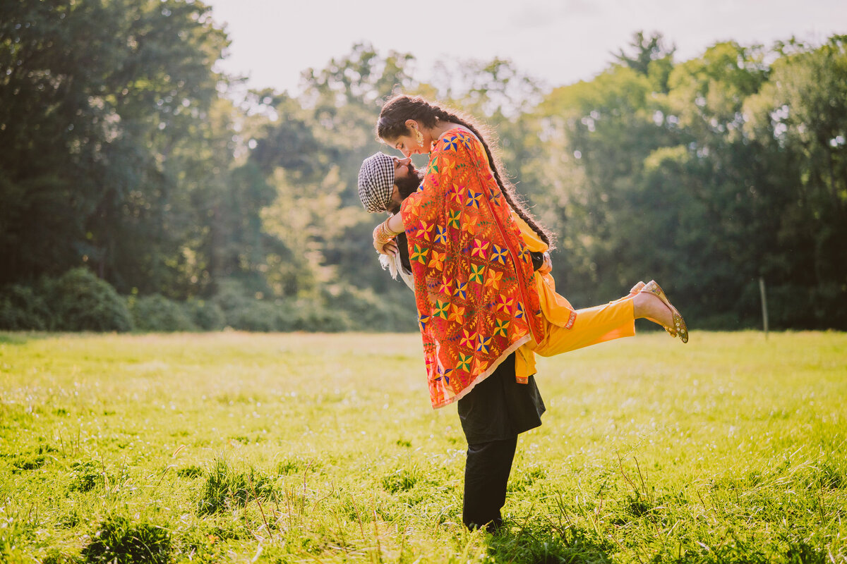 bride being picked up by the groom during their engagement session in traditional sikh punjabi clothing in nj