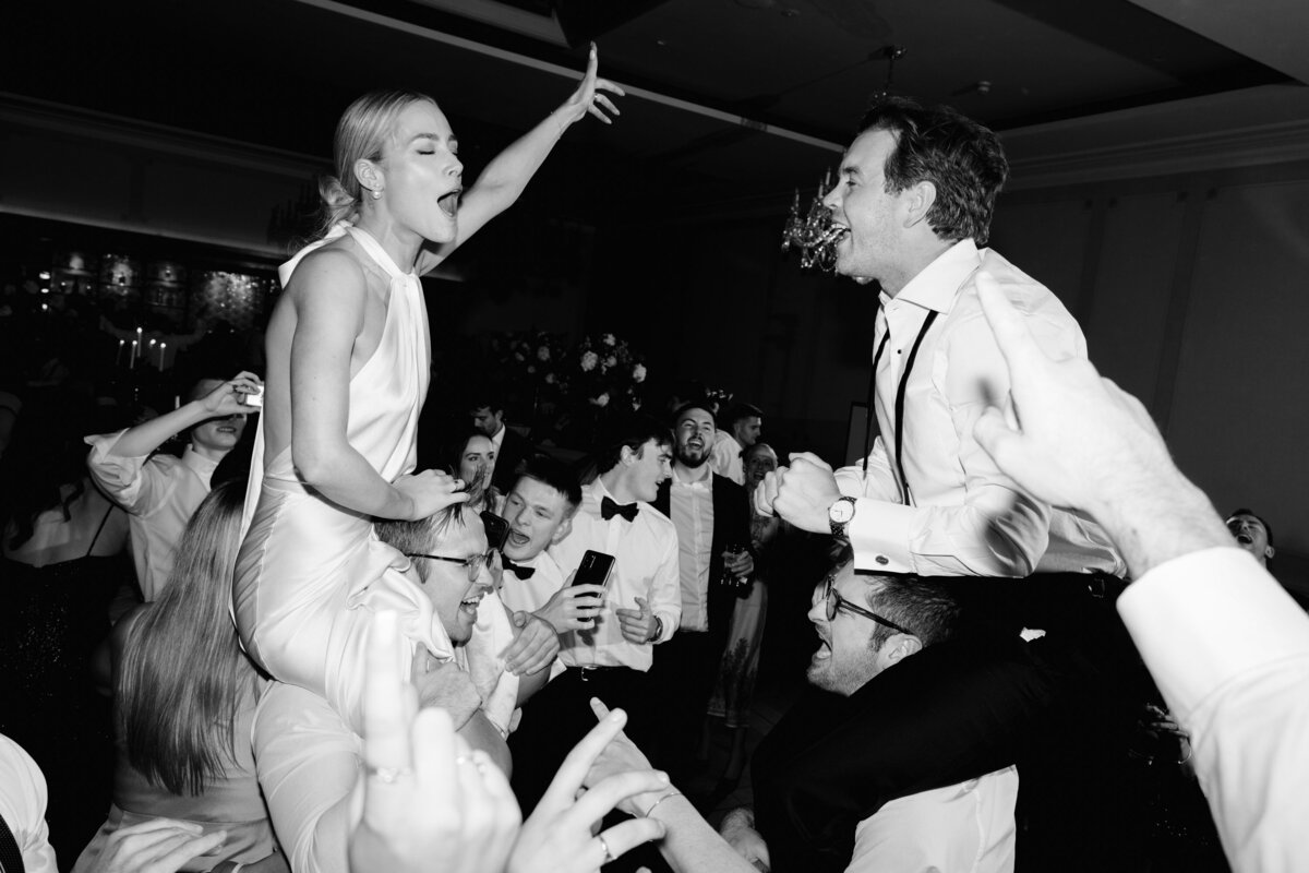 bride and groom on the guests shoulders on the dancefloor