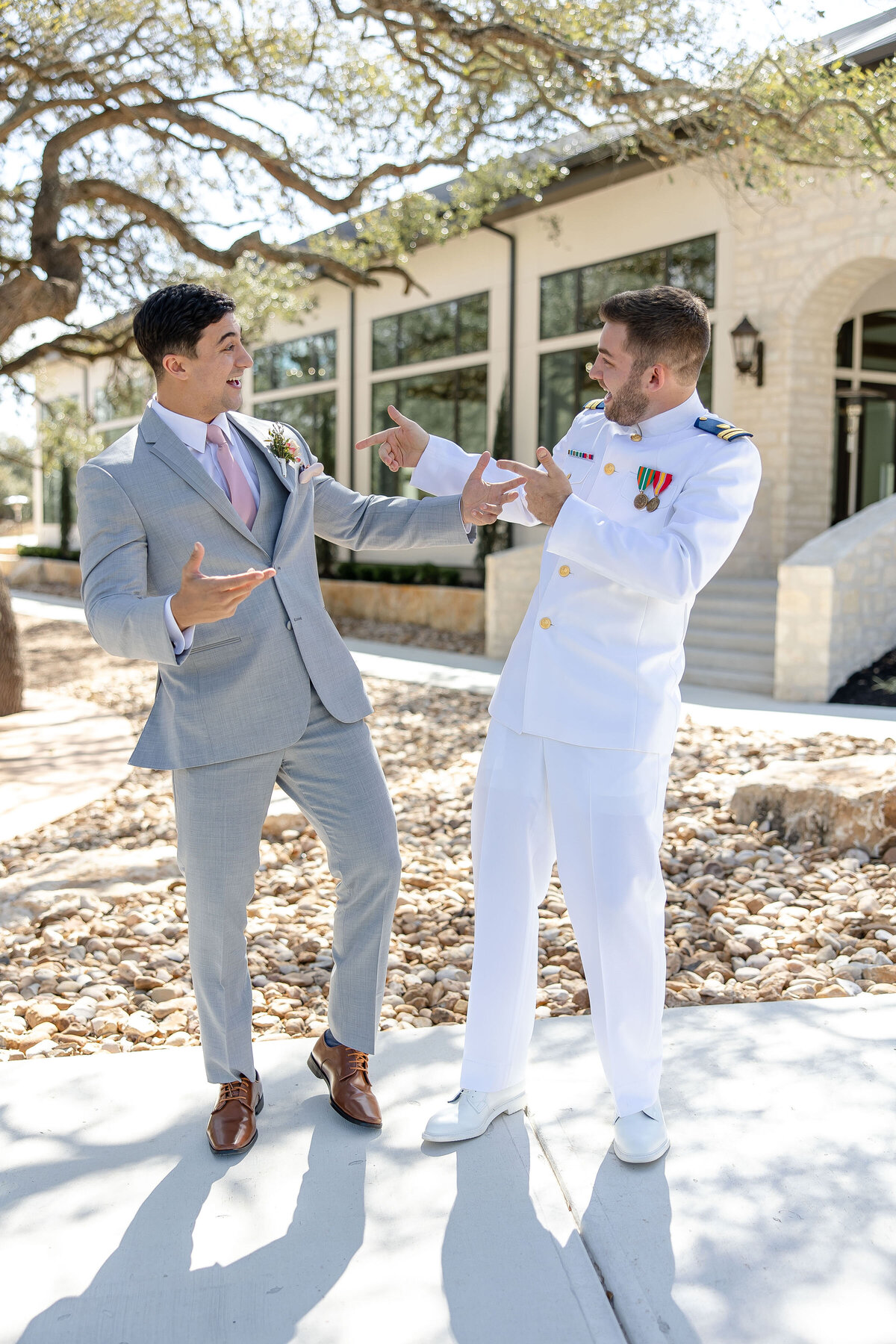 groom in military uniform and groomsman in gray suit playfully smile at The Preserve at Canyon Lake Texas wedding