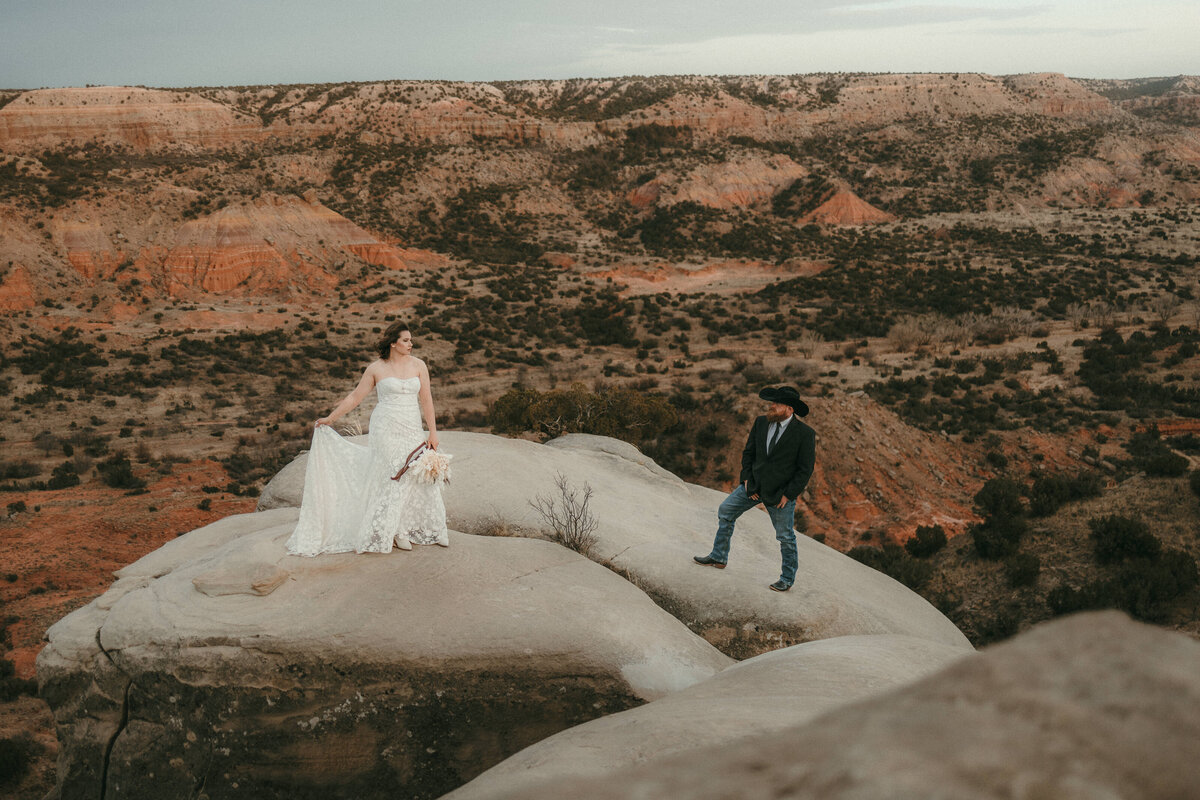 Bride and groom standing on yellow bear rock in Palo Duro