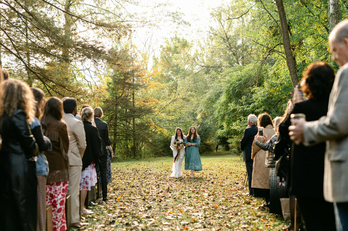 Bride walking down the aisle with women hand in hand