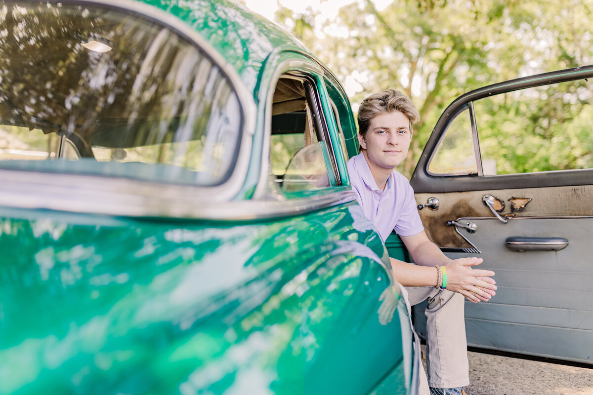 Senior boy poses in antique car for senior session at the town of livingston in flora, MS.