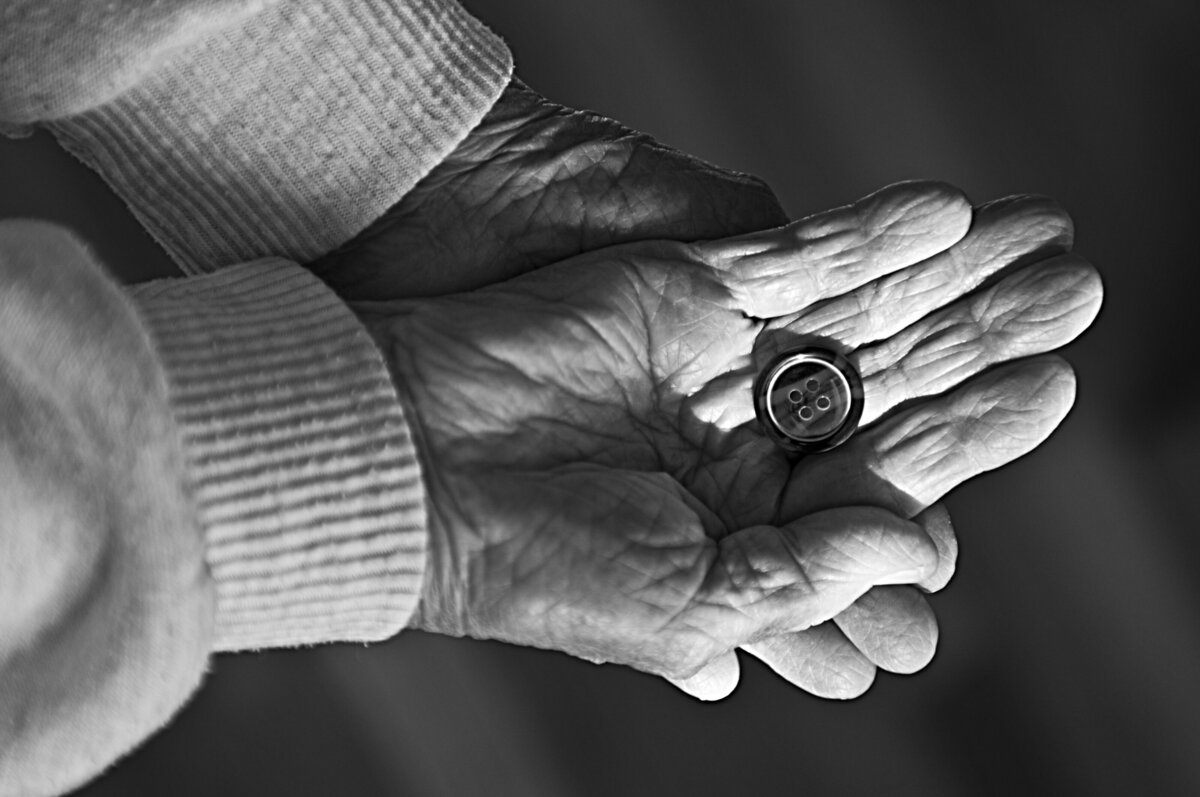 Two hands stacked on top of each other with a button in the middle