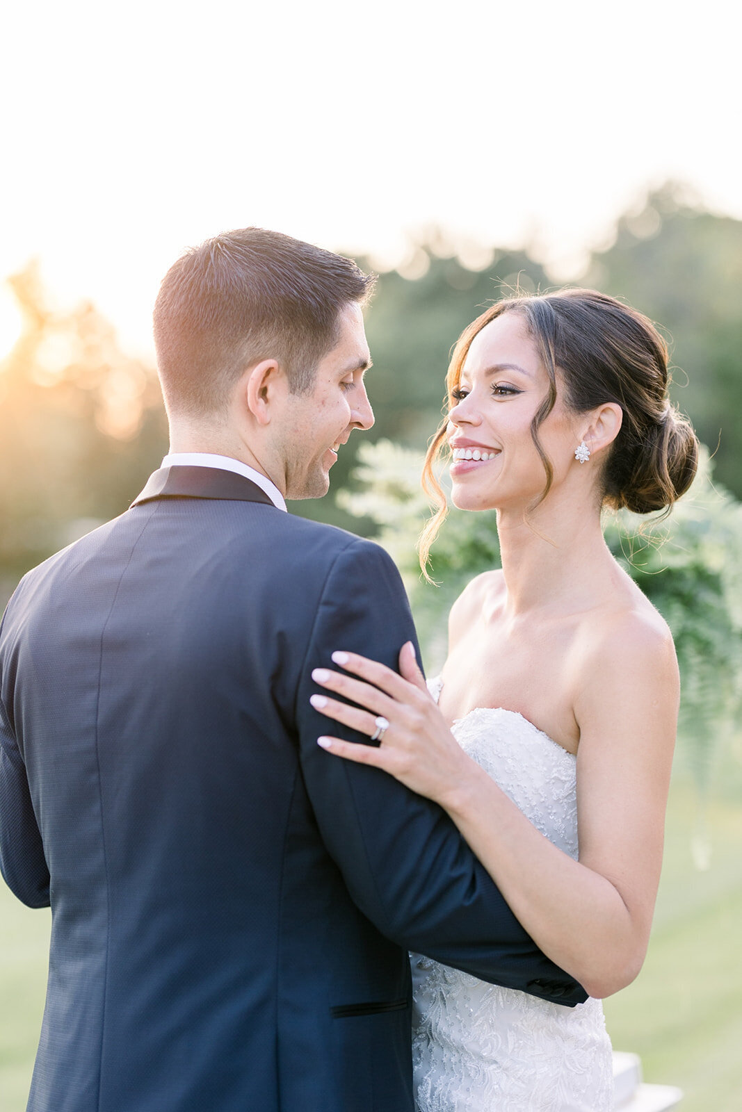 Newlyweds dance and smile  in a garden lawn at sunset