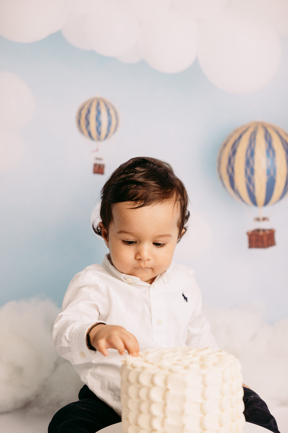 A little boy with a hot air balloon  backdrop during a cakesmash photoshoot with auckland photographer michelle kelly