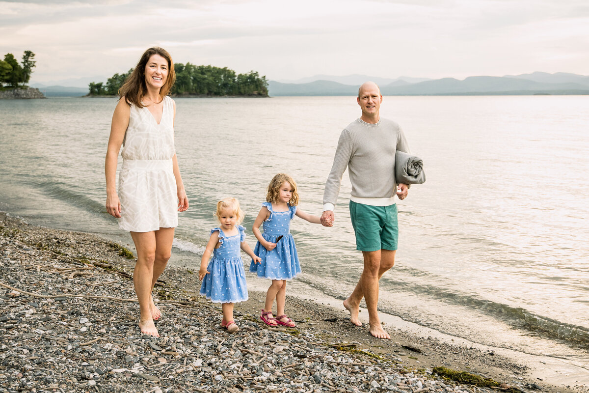 mom and dad walk on the beach with their young daughters Burlington Vermont Family Photographer