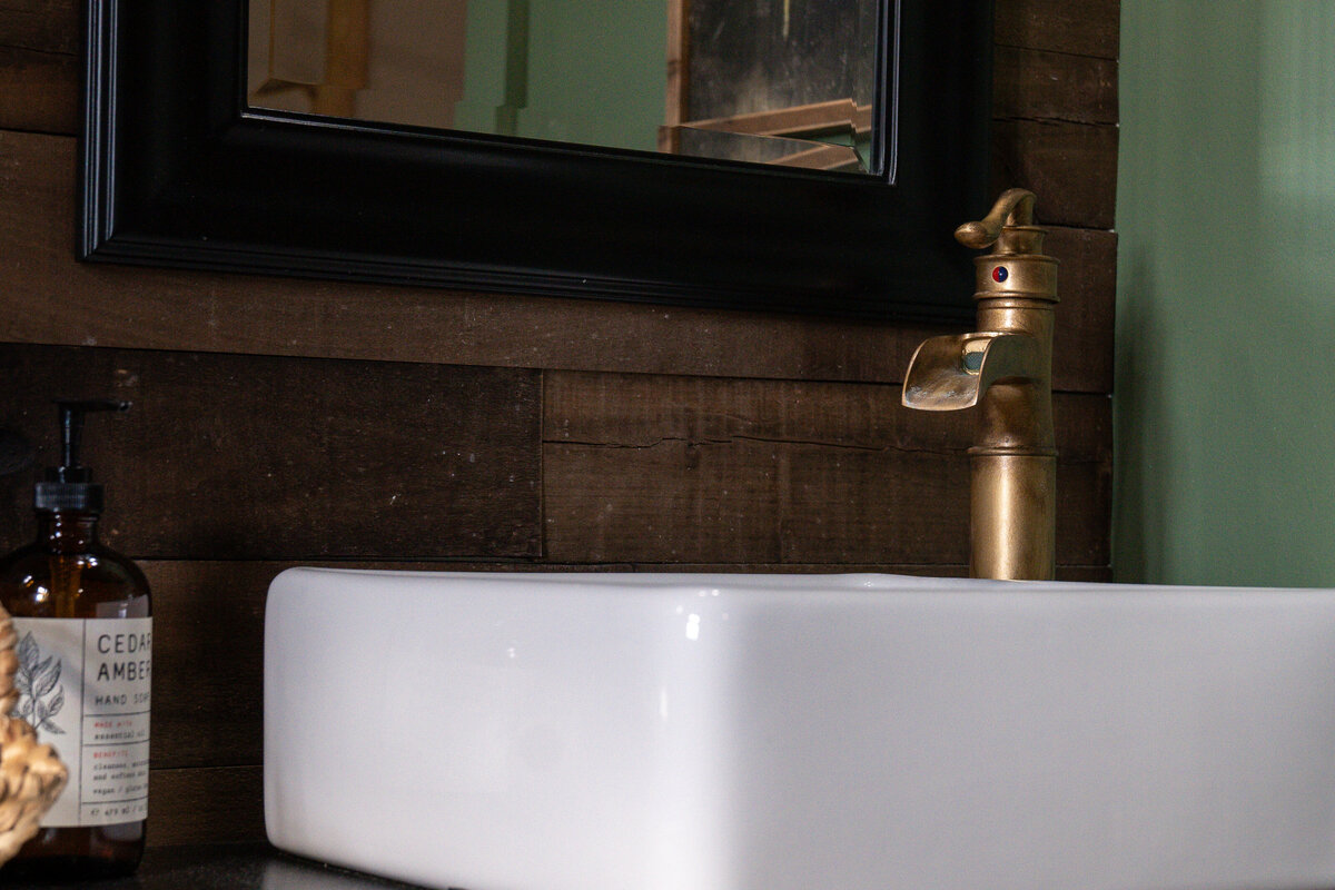 Vessel sink on top of the black cabinet with brass colored faucet