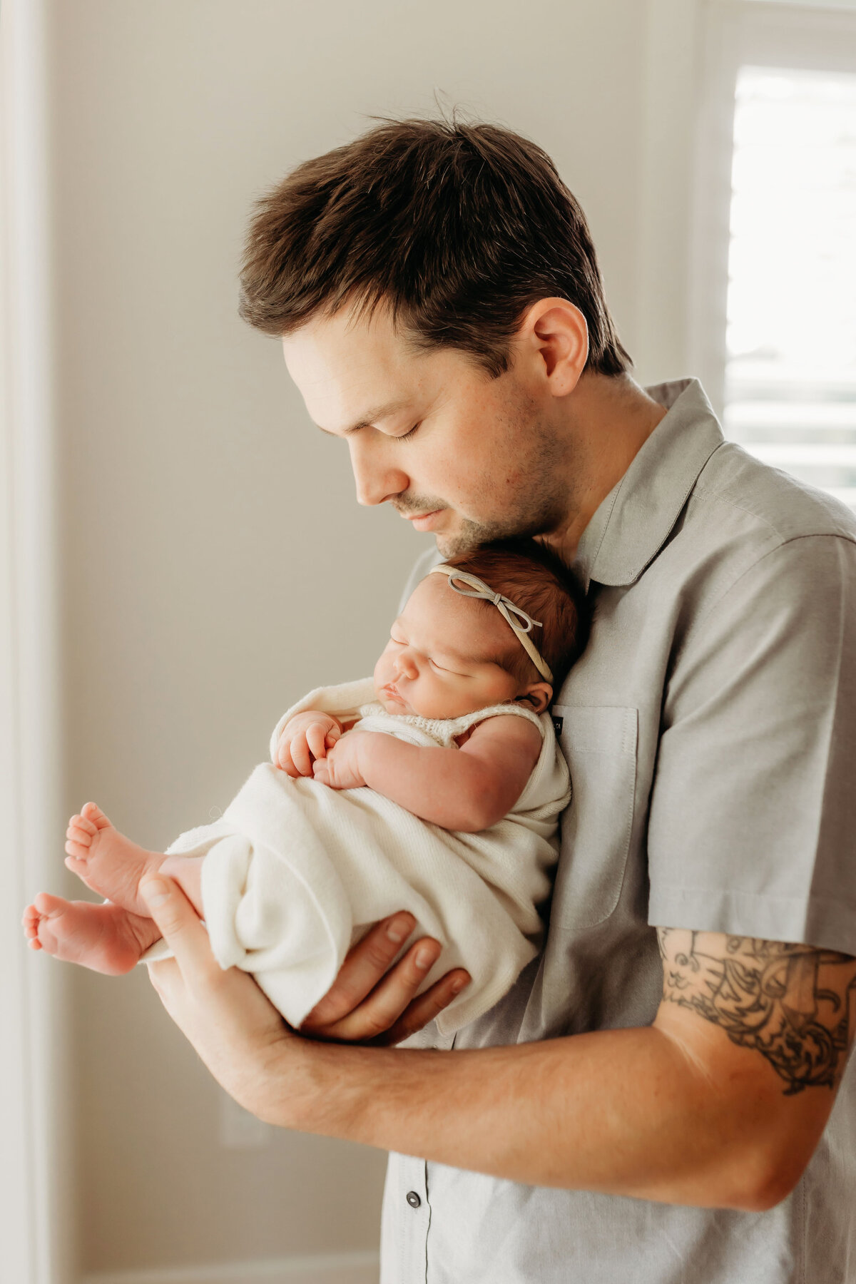 A dad lovingly holds his newborn baby inside his home, as photographed by a Vancouver Washington newborn photographer