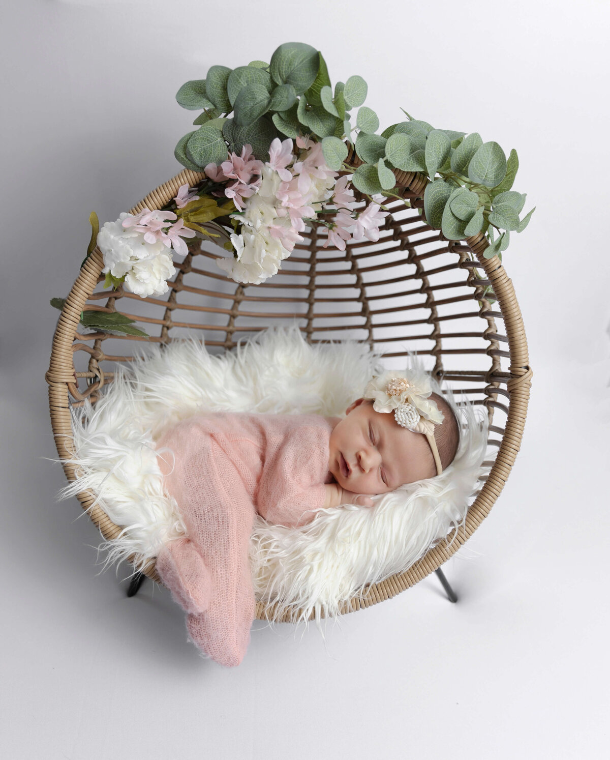 Newborn photo of a baby girl in a pink sleeper posed in an Erie Pa photography studio