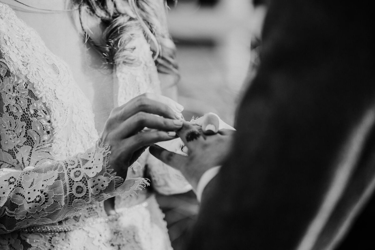Bride slides wedding ring onto groom's finger