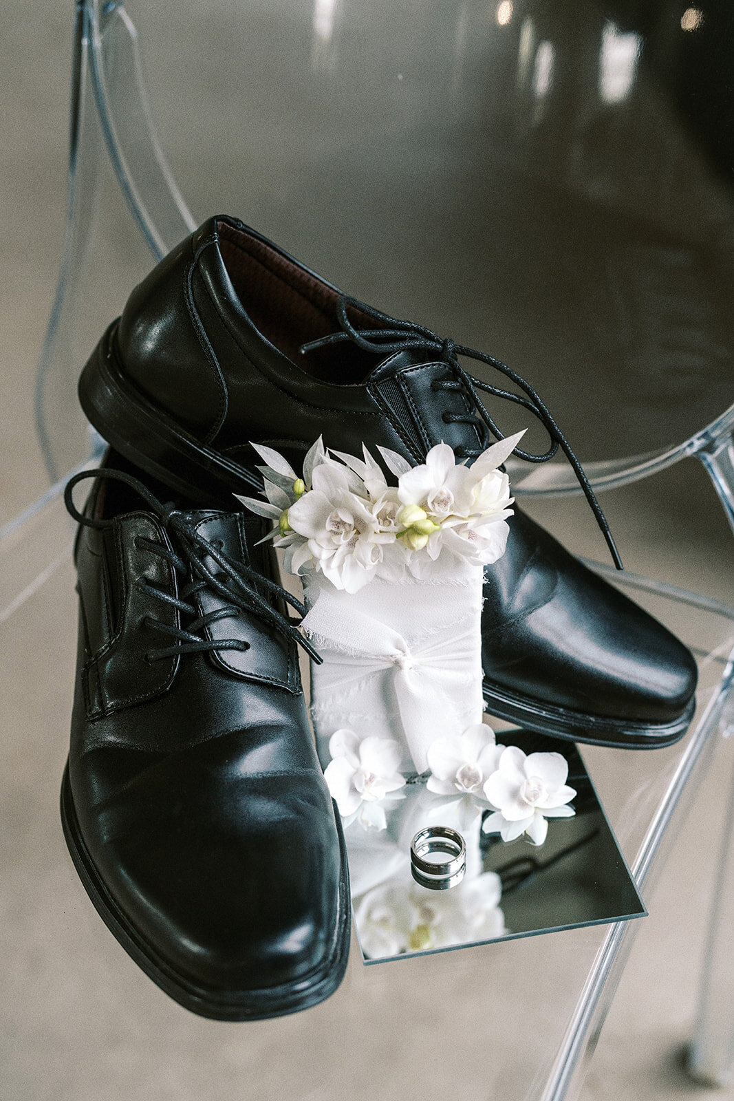 A pair of men's dress shoes, wedding ring and flowers at a styled wedding photography shoot.