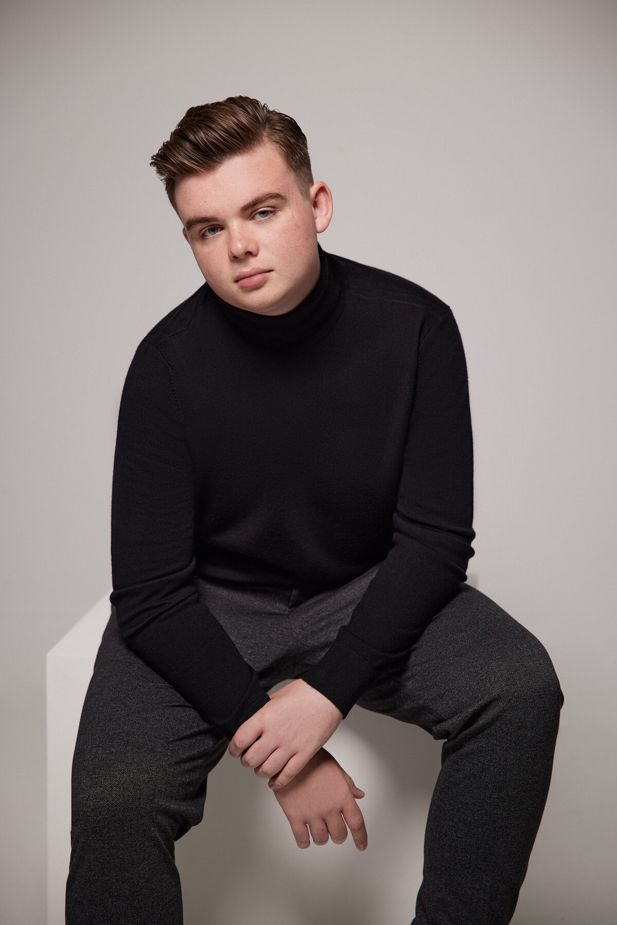 A young boy sitting on a white block