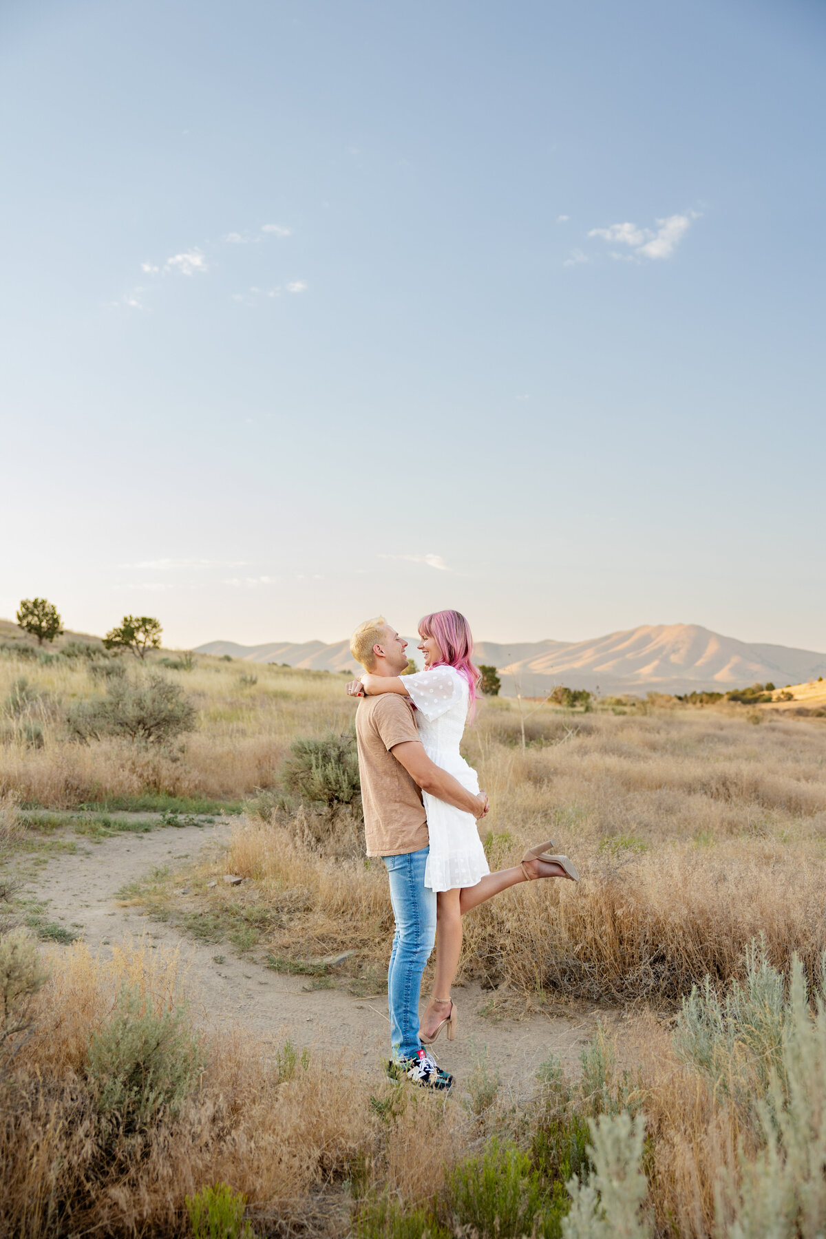 Husband and wife share a kiss as he lifts her up and her foot pops