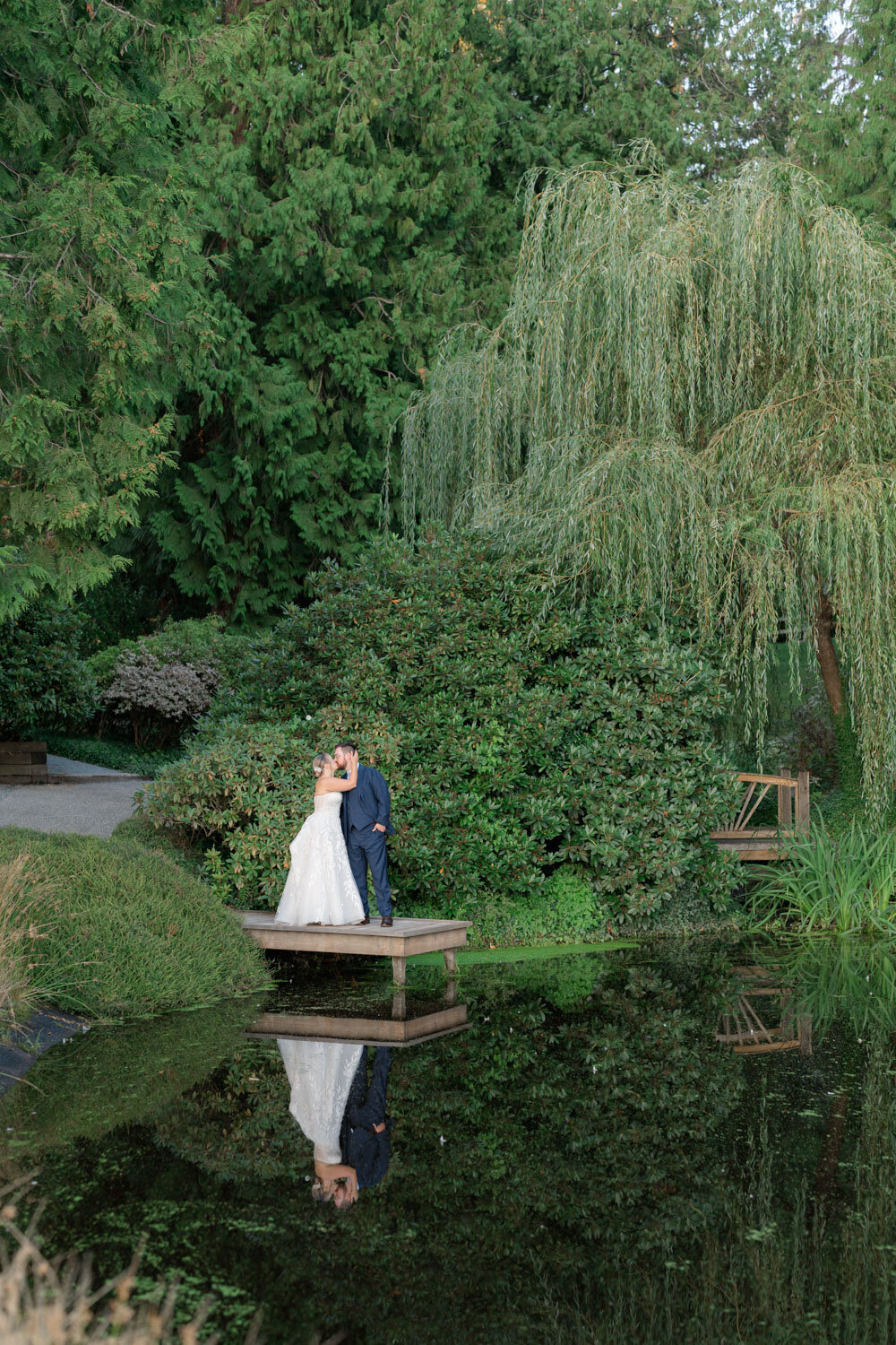 Couple kissing on a wooden dock by greenery