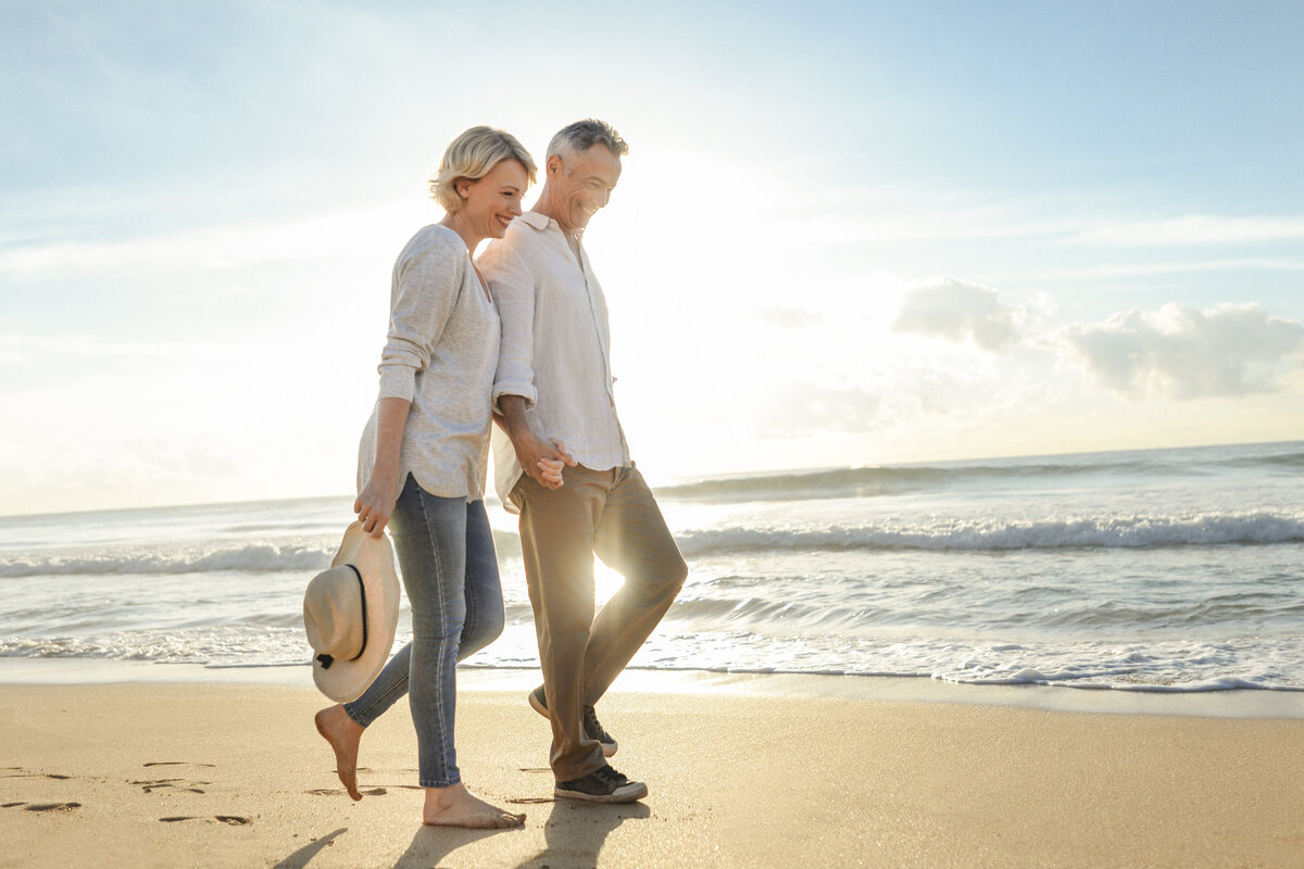 Middle-aged couple walk the beach together.