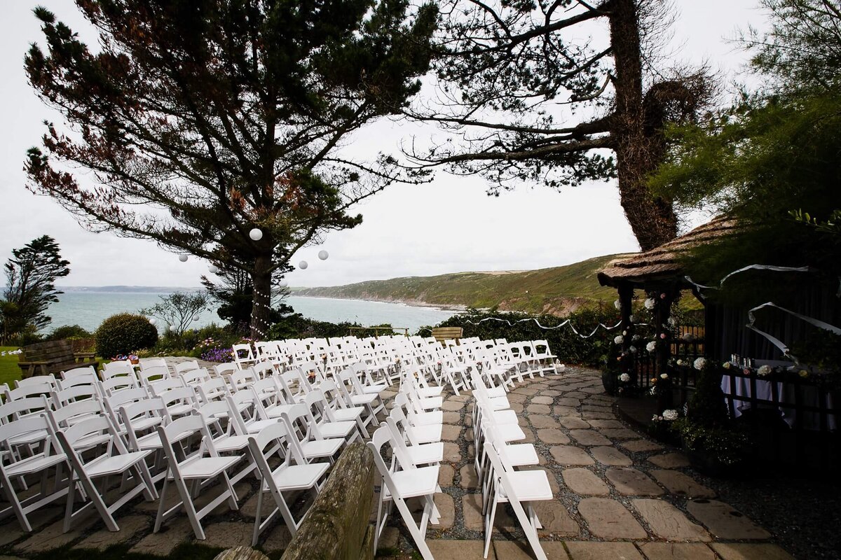 Rows of white chairs set up for an outdoor wedding ceremony