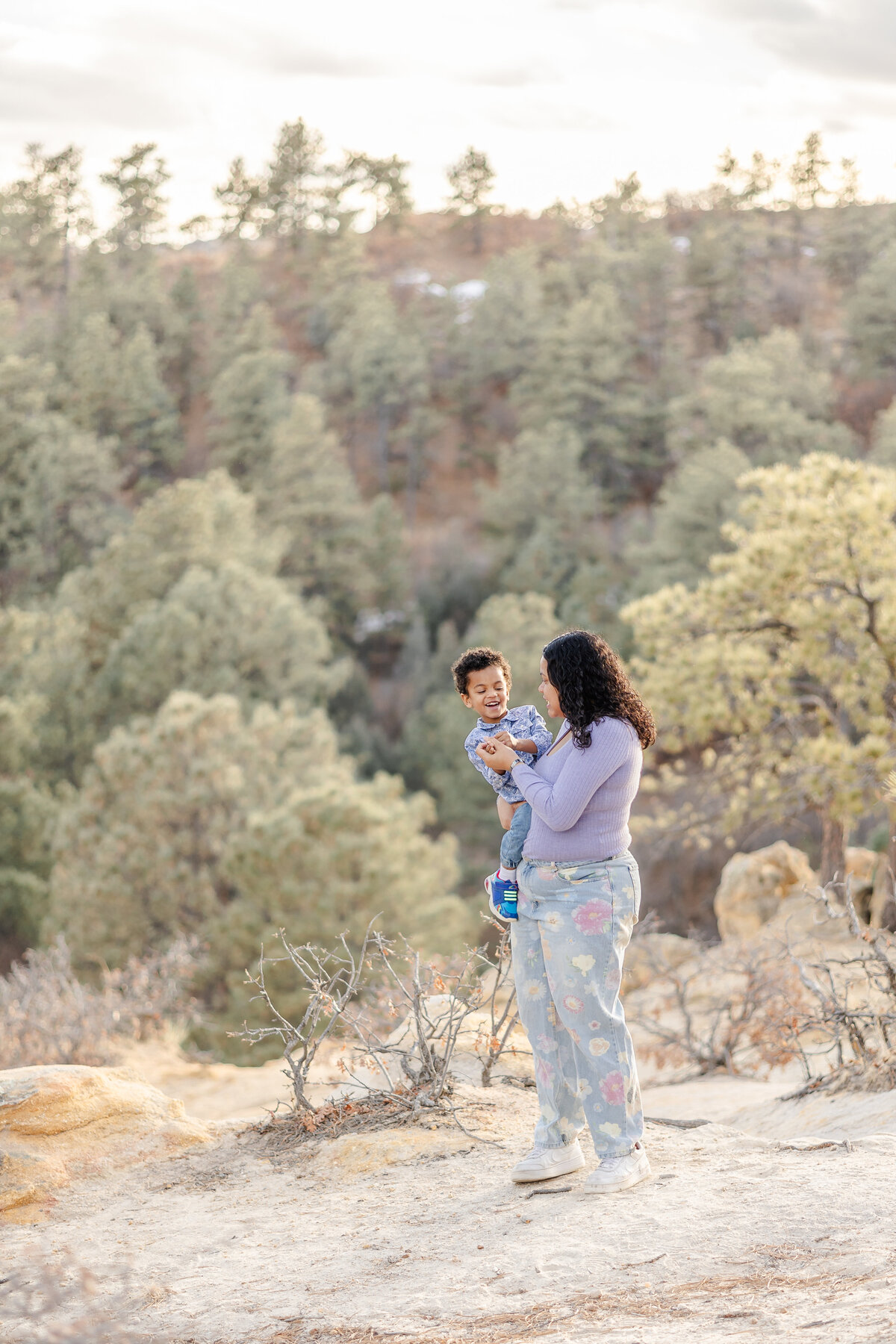 Colorado Springs Family Photographer - Mom holding young son in front of trees and mountains