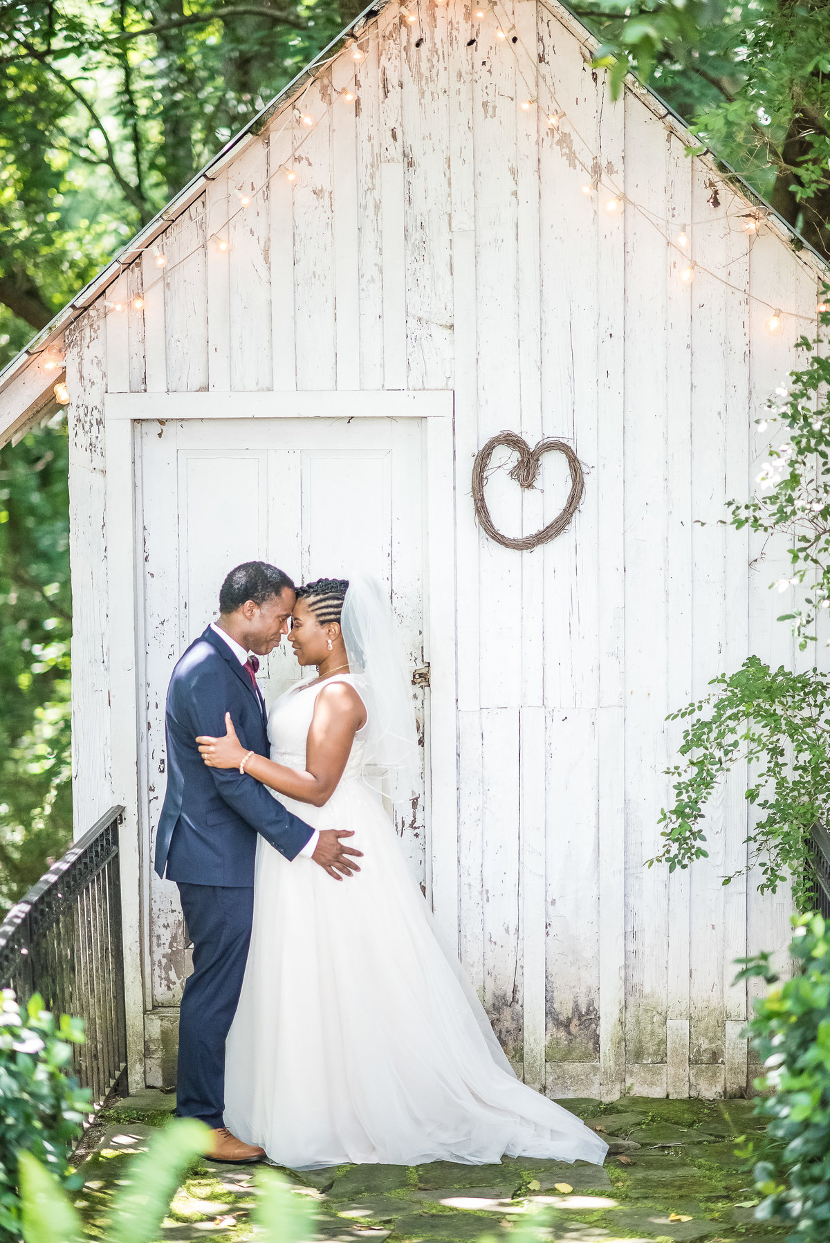 bride and groom facing each other in front of barn
