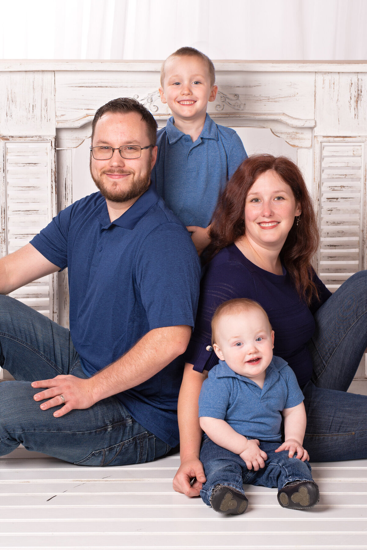 Intimate studio family portrait on a white backdrop, showcasing a family of four, captured in Overland Park, Kansas. A timeless choice for families seeking classic and meaningful photography in the Kansas City metro area.