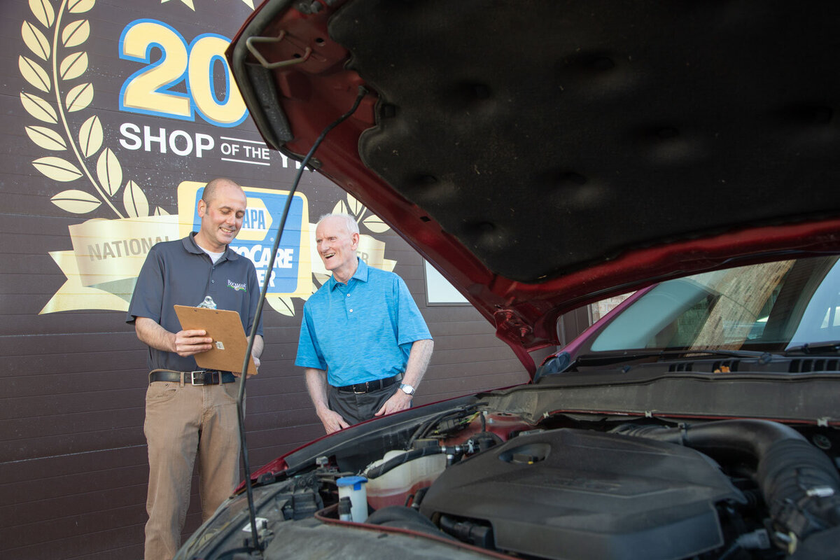 Two men looking under the hood of a car
