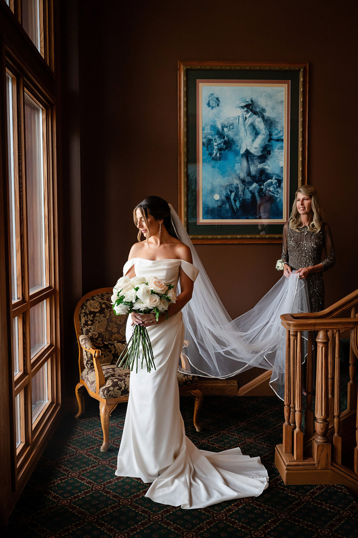 bride and mom fixing veil on staircase of southpointe golf club before wedding ceremony