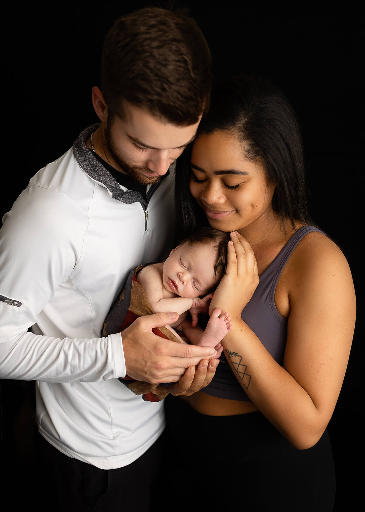 Baby boy posed with his mom and dad during his newborn portrait session.