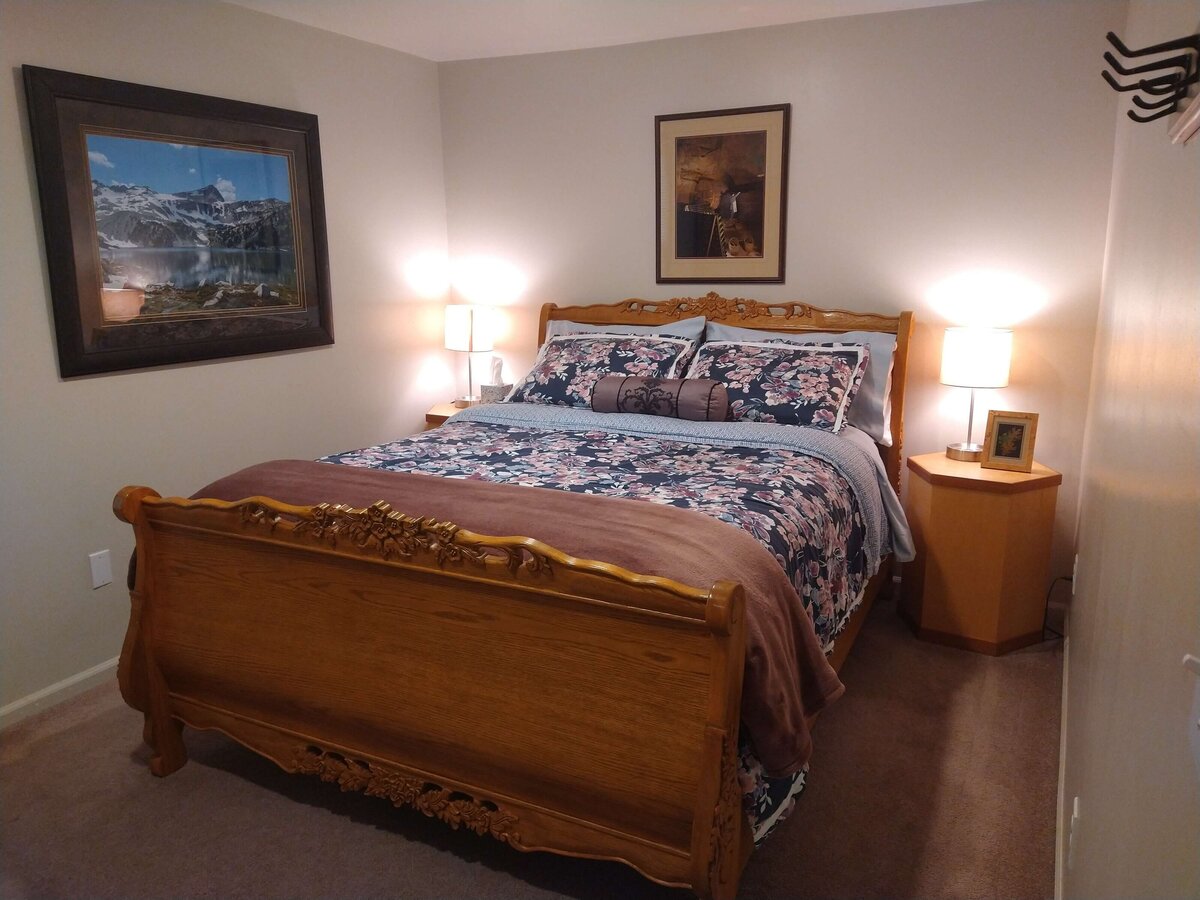 Queen size bed with bedside table and art on walls in private bedroom.