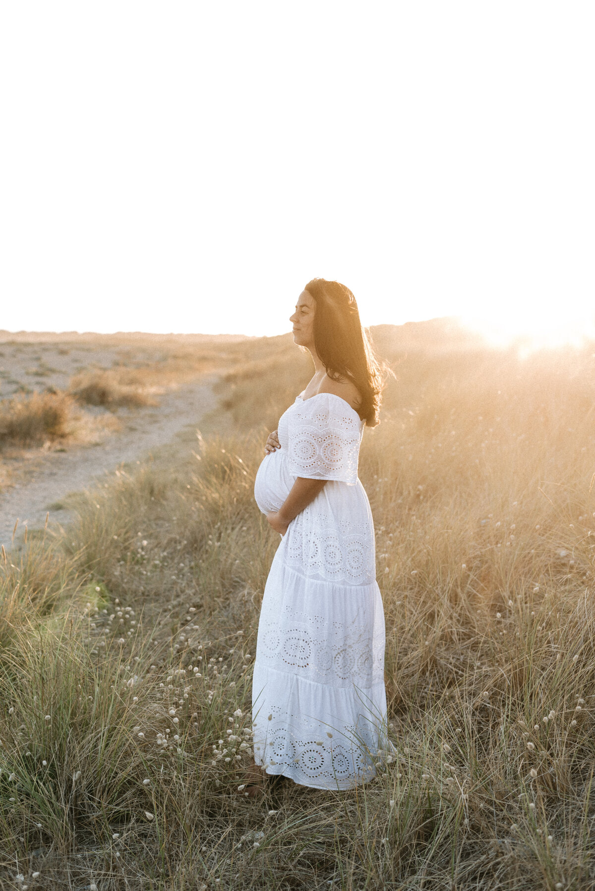 A women standing on the dunes during sunset at a billingshurst maternity photoshoot