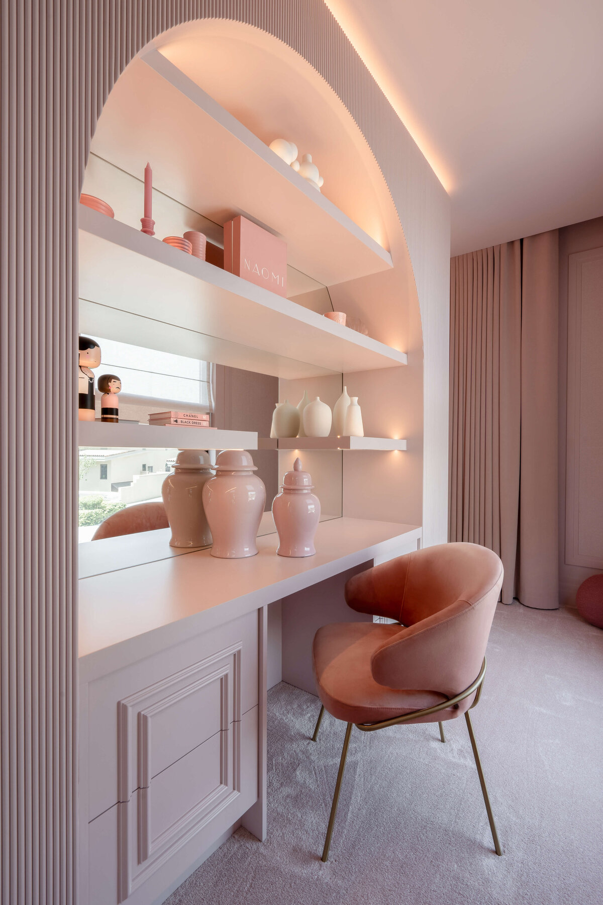 Details of built-in desk in girl's pink bedroom show additional built in shelving and a glass back. The built-in is completely pink and decorated with chic pink decor.