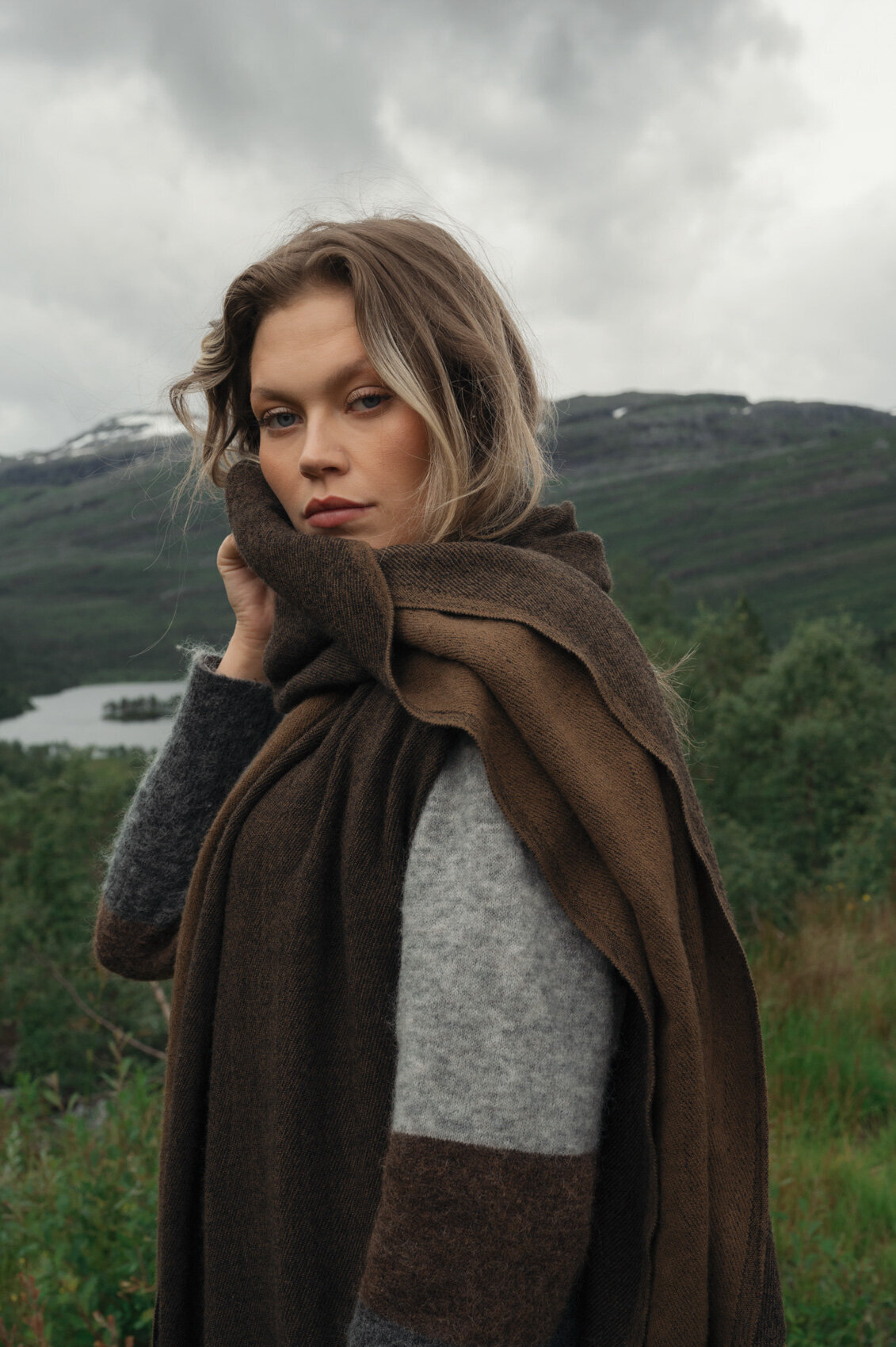 Fashion model standing in the Scandinavian landscape in grey coat