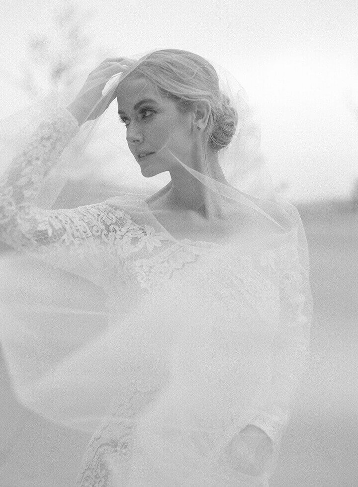 Bride pushes her hair out of her face as the wind moves through her veil