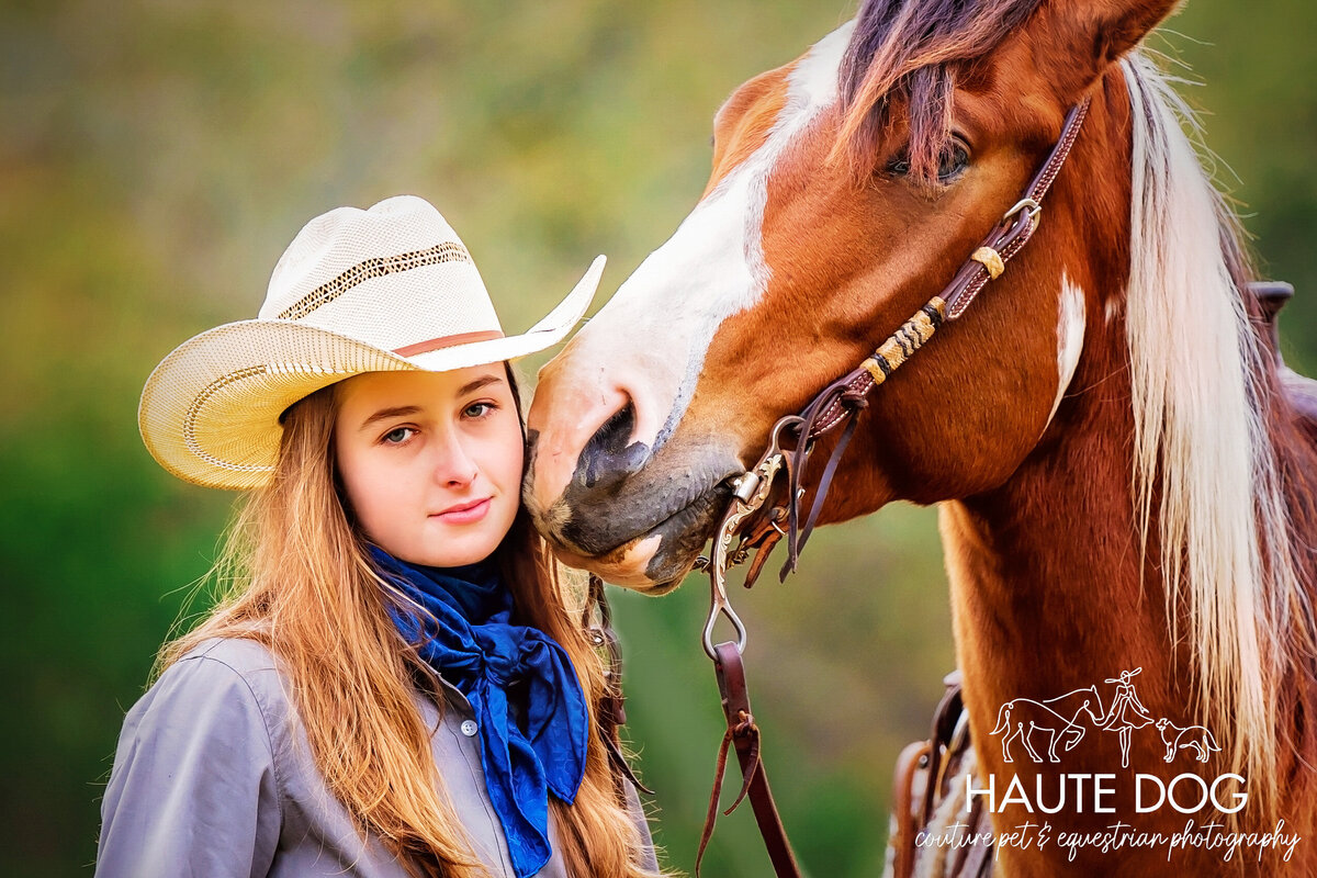 Close up of a Paint horse nuzzling a female equestrian wearing western attireon the cheek.