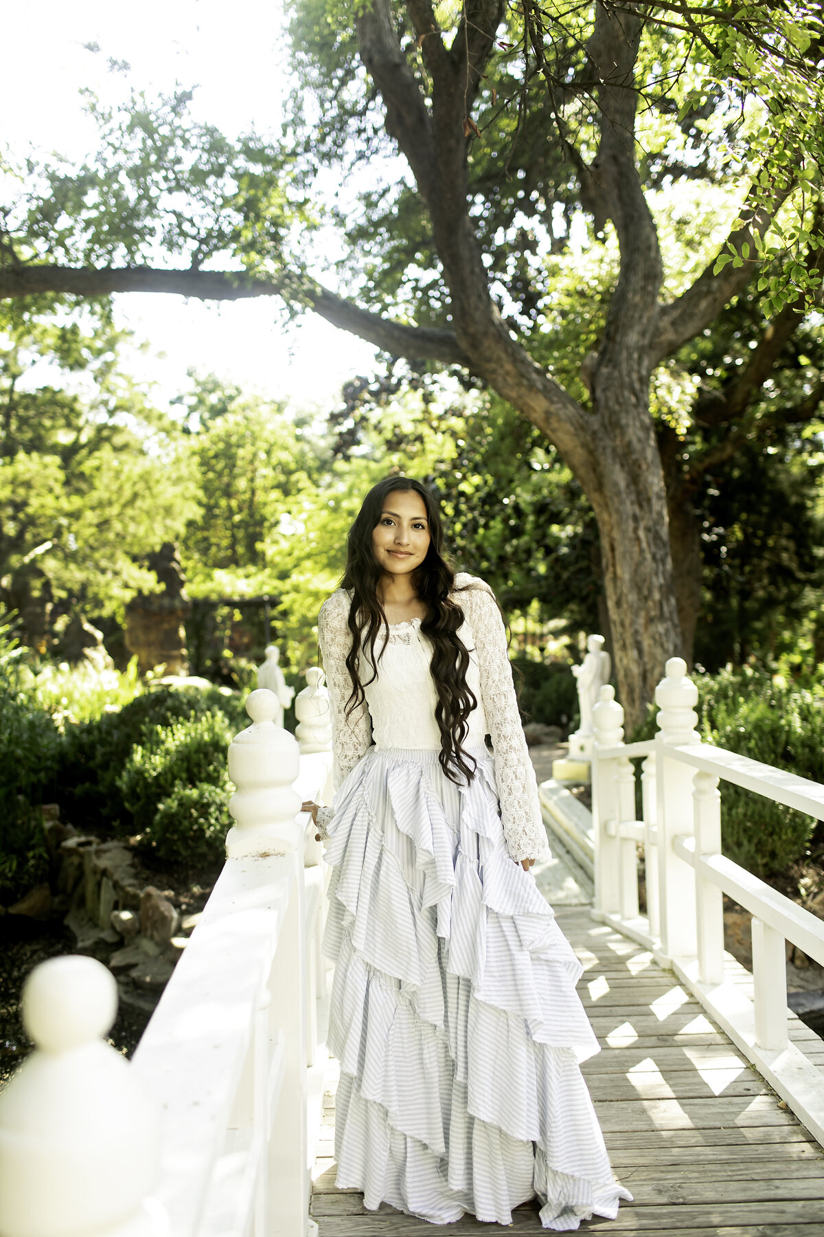 A high school senior exuding joy and confidence while surrounded by the stunning blooms of Chandor Gardens, Weatherford, TX, as she celebrates this important milestone