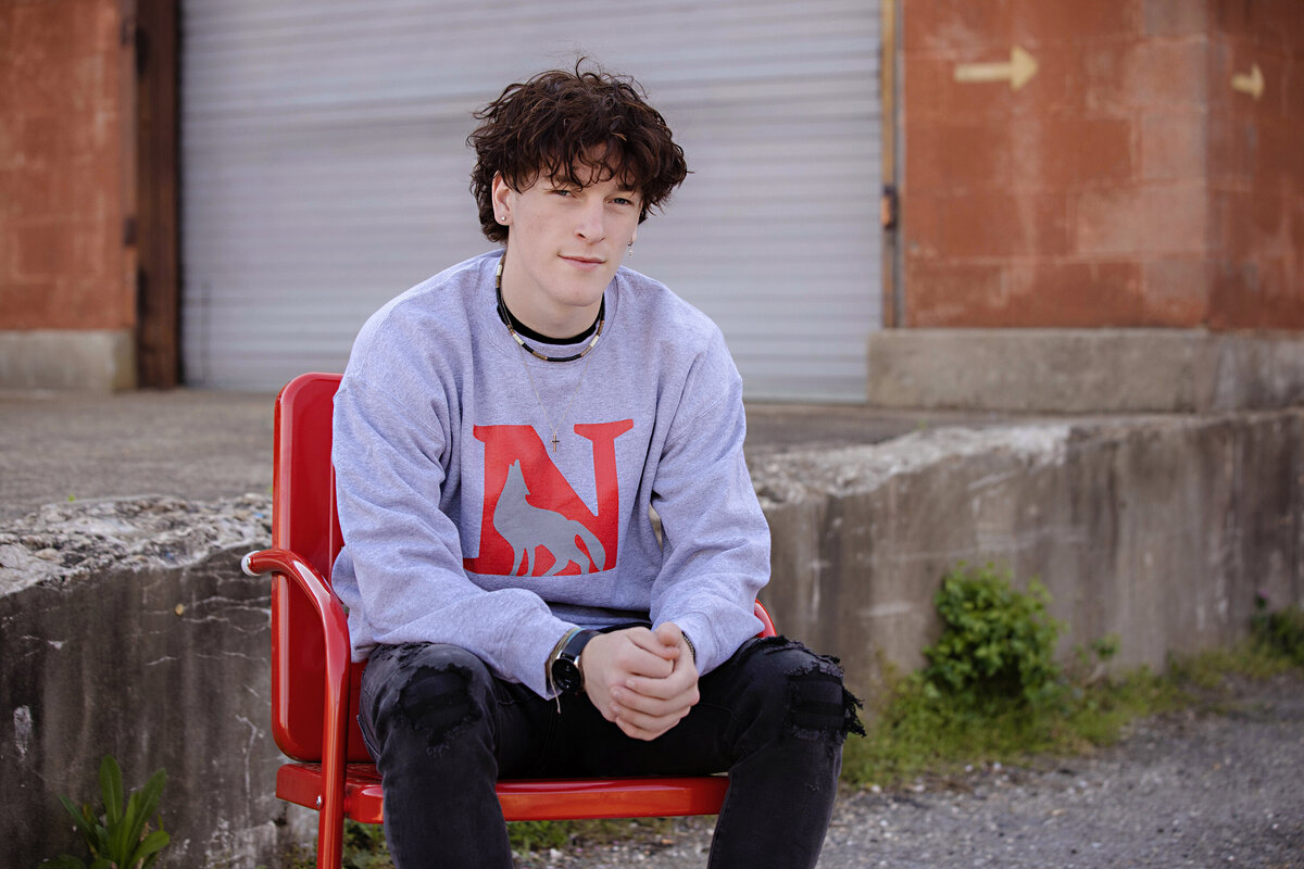 Editorial senior portrait featuring college pride and athletic style, captured by Charlotte photographer in an industrial setting at Camp North End.
