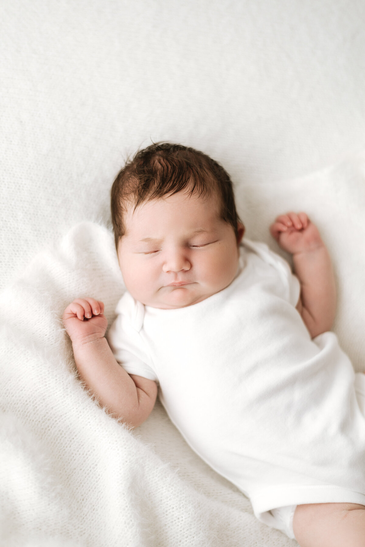 Baby girl sleeping on a white blanket in Billingshurst newborn photoshoot