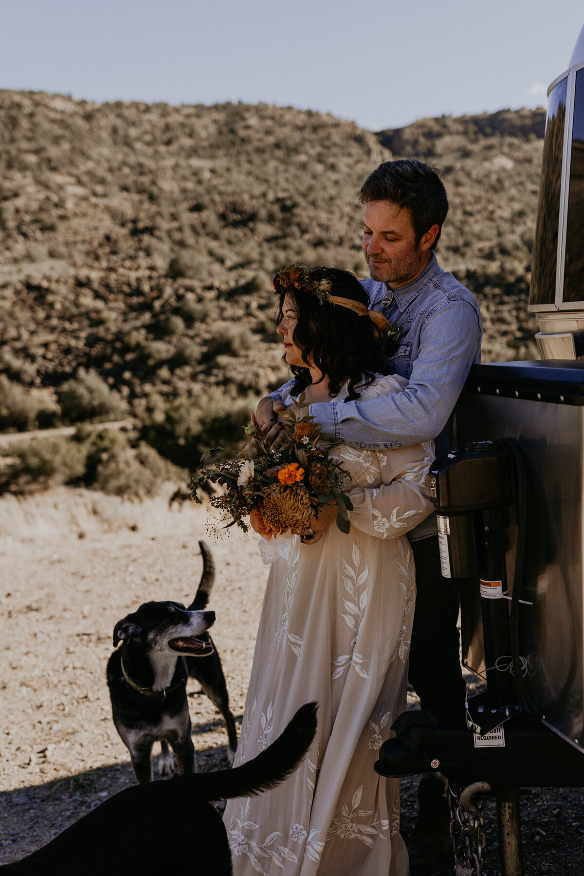 bride and groom with their two dogs and airstream camper