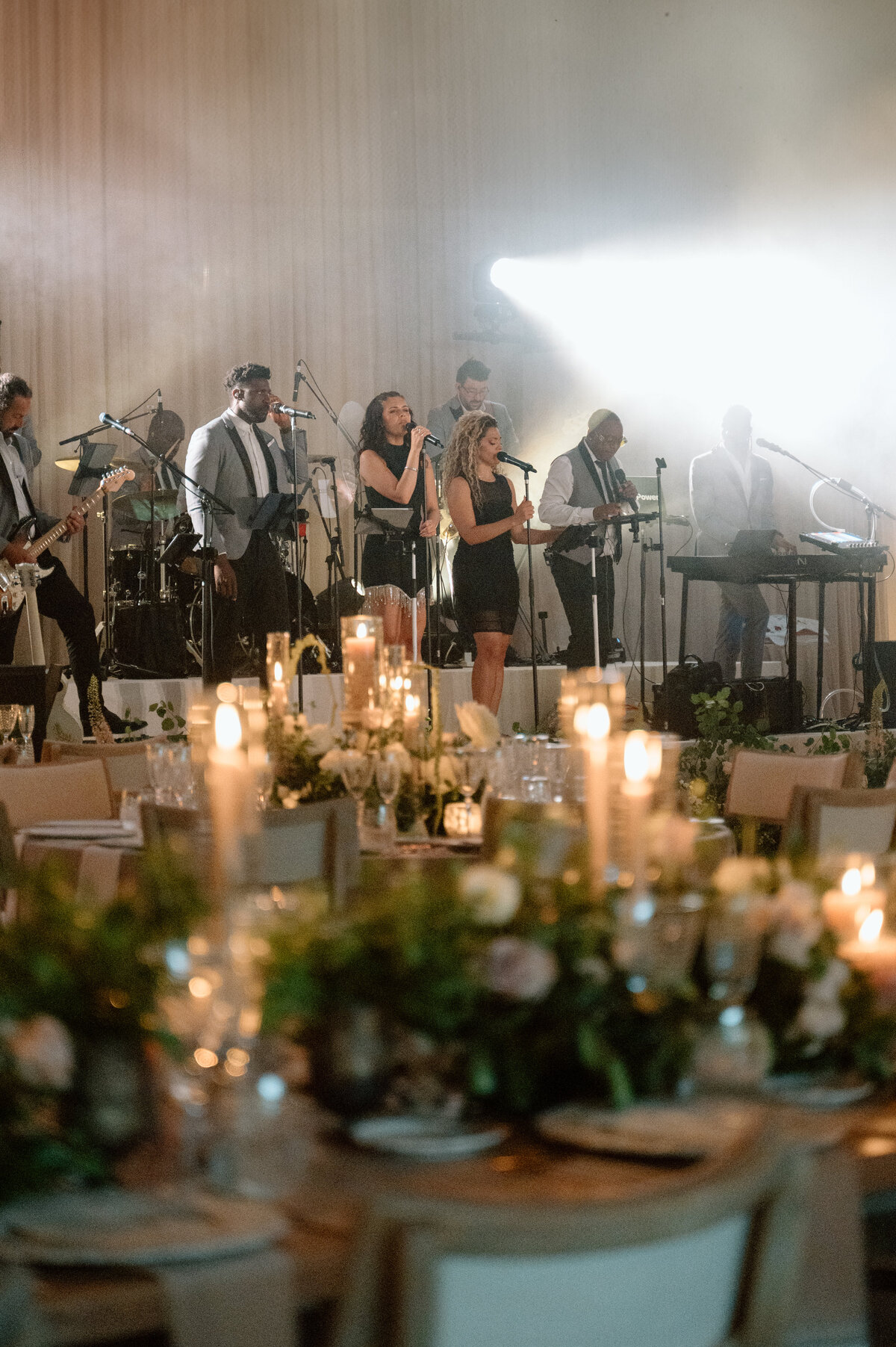 Band playing under spotlight at elegant wedding reception.
