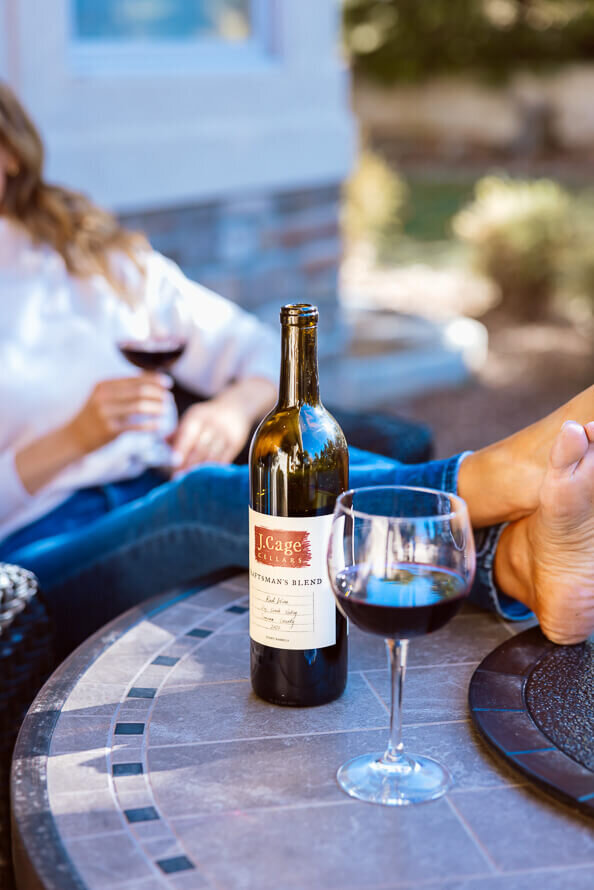 Glass of wine and a wine bottle with a woman with her feet up in the background as a part of her branding session.